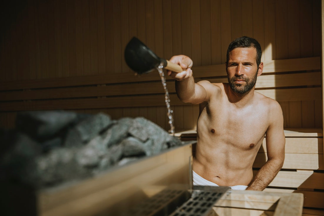 Man pouring water on the hot stones in the sauna.