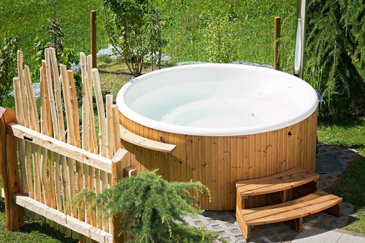 Jacuzzi in the backyard with wooden fence.