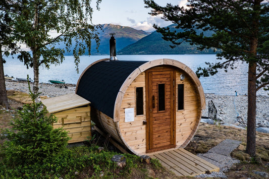 Black-roofed barrel sauna by a lake.