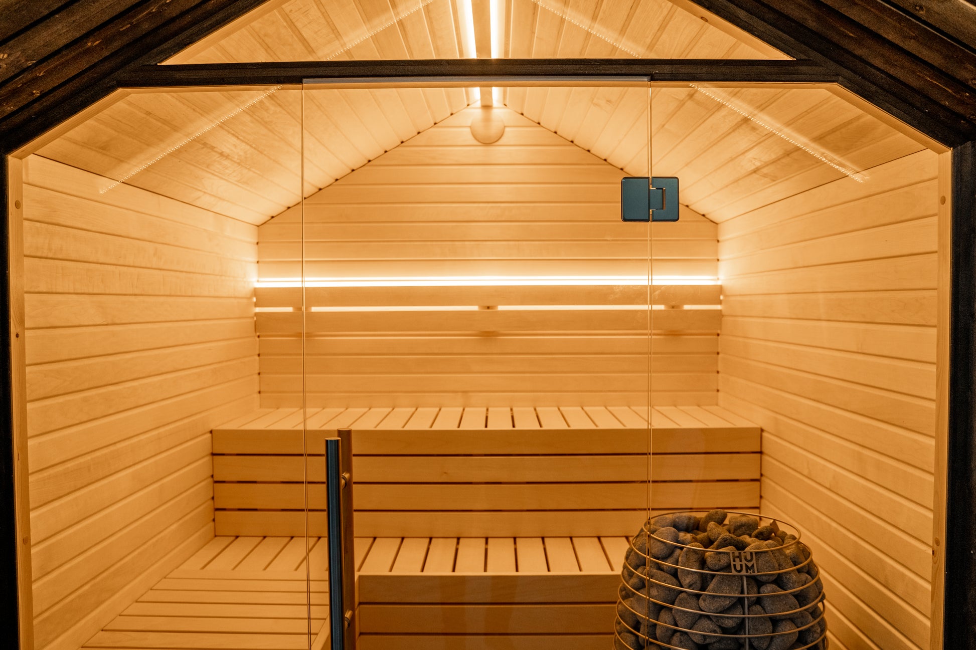 LUMI sauna with glass wall and stone basket.