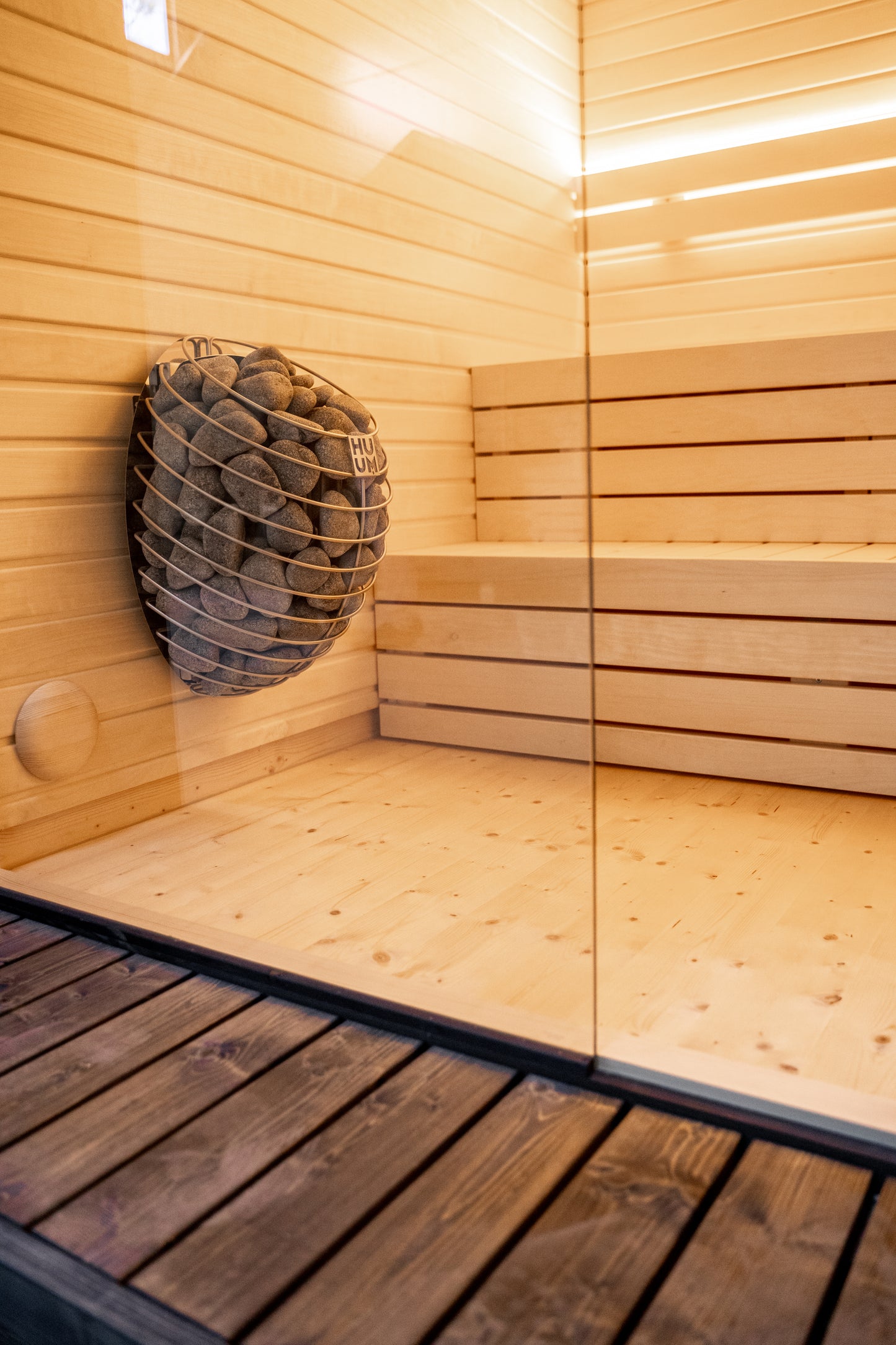 LUMI sauna with stone basket and glass wall.