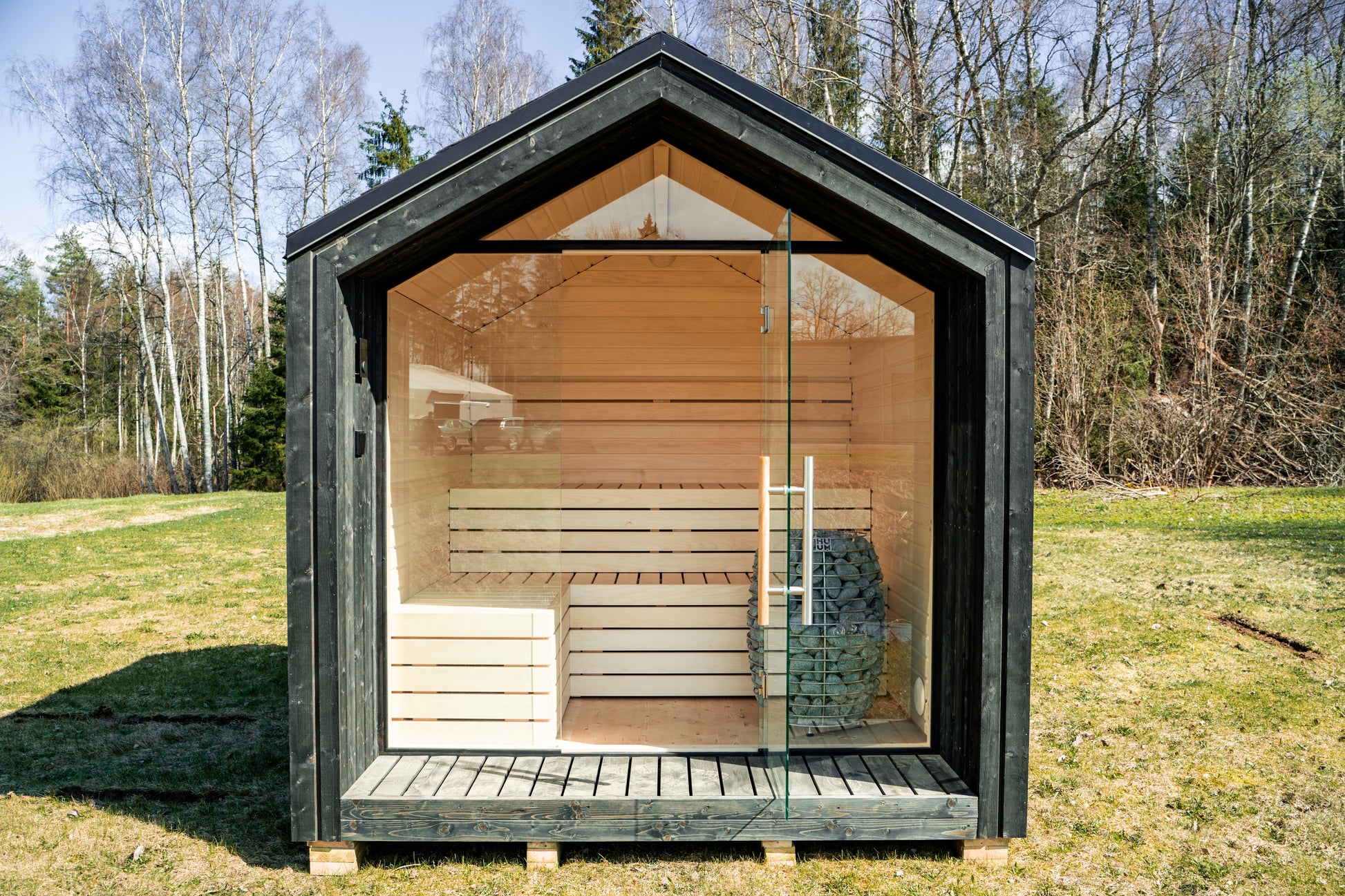 Isolated outdoor sauna Saunamo Lumi in a grassy area.