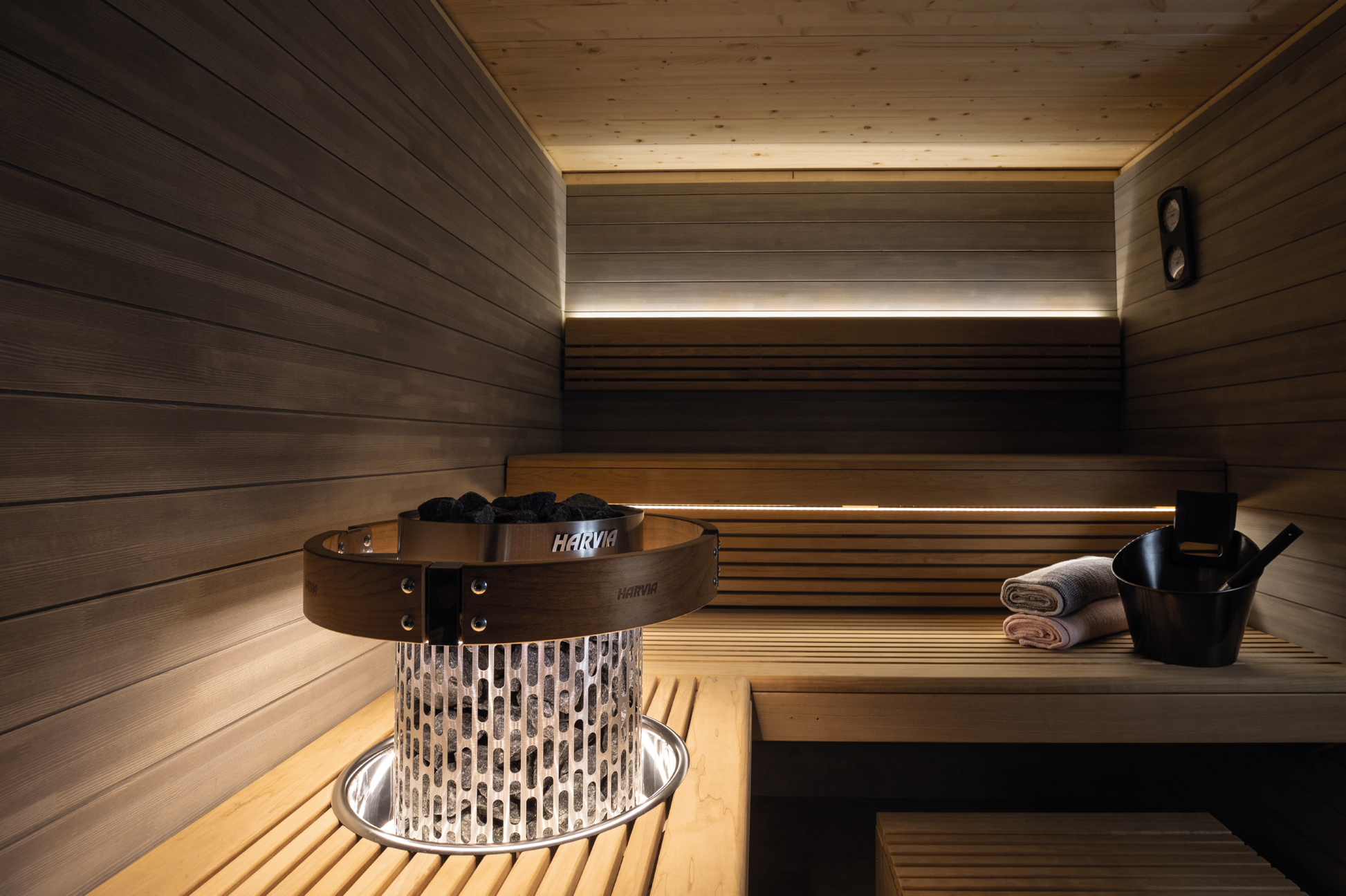 Harvia LED lighting set in sauna with stones and bucket.