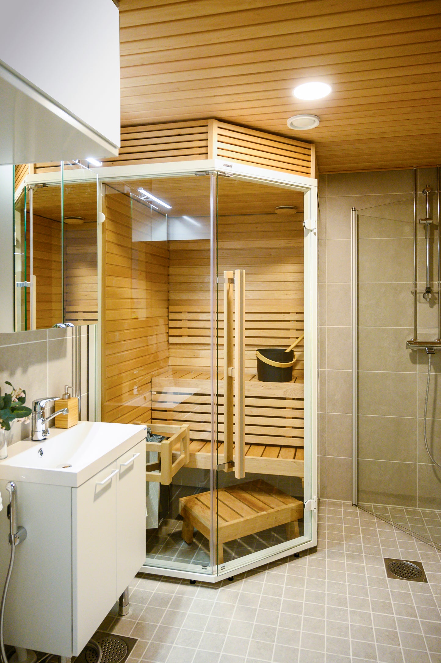 Sirius Corner sauna with sink and wooden bench.