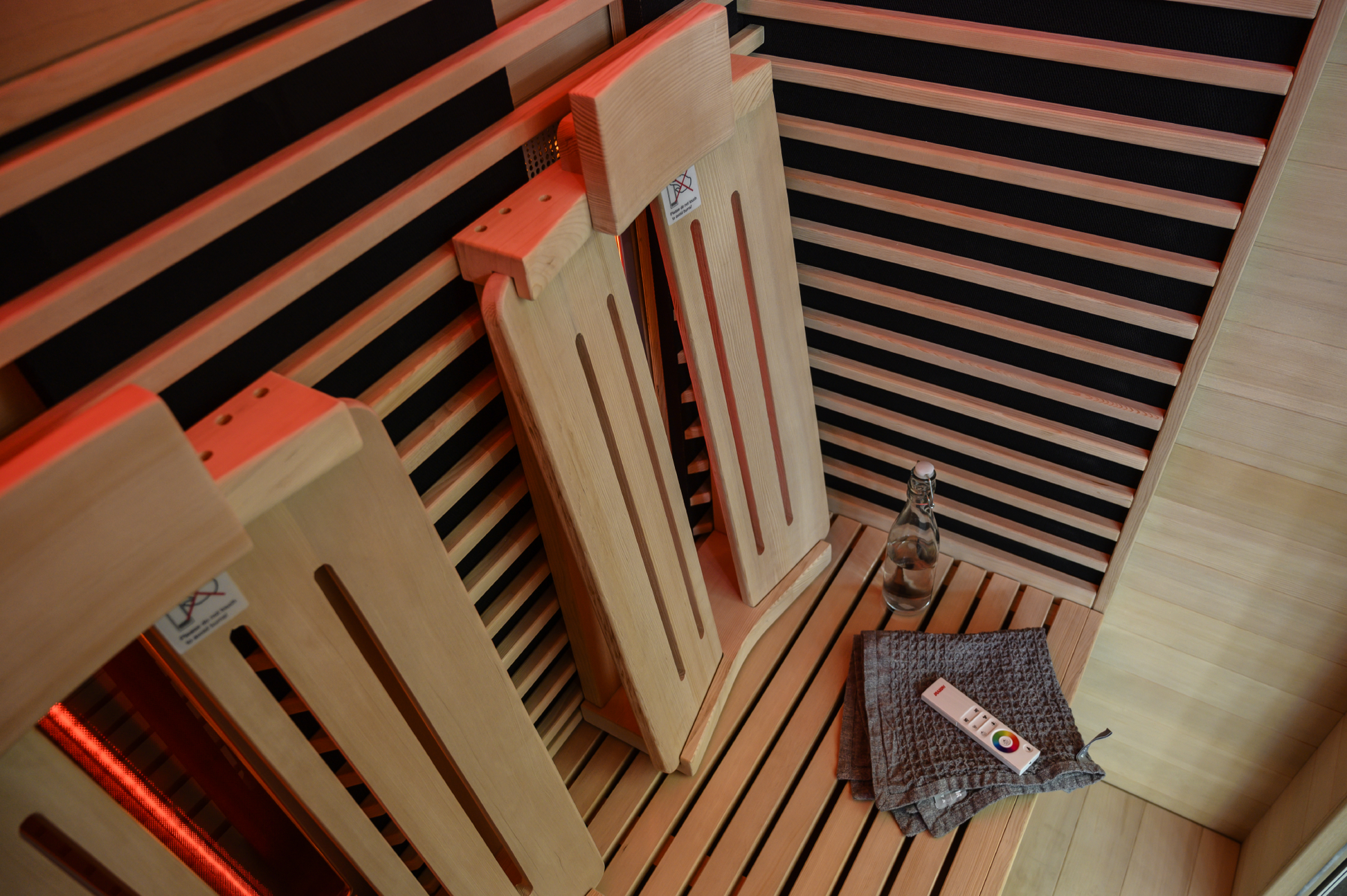 Spectrum infrared sauna with wooden chairs and remote control.