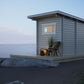 Outdoor sauna Saunamo Nordica on the beach with chair and plant.