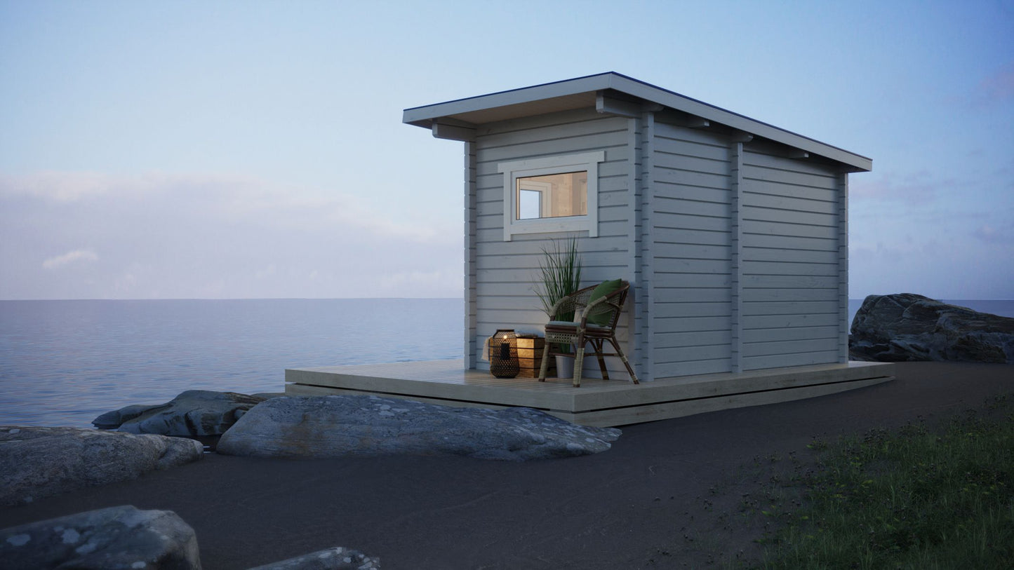 Outdoor sauna Saunamo Nordica on the beach with chair and plant.