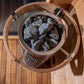 KUUT L wood-fired outdoor sauna with stones in a bucket.