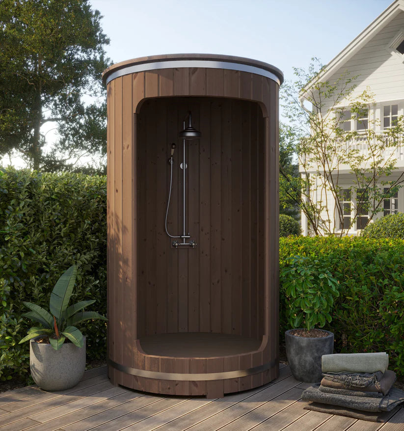 Outdoor barrel shower with plants all around.