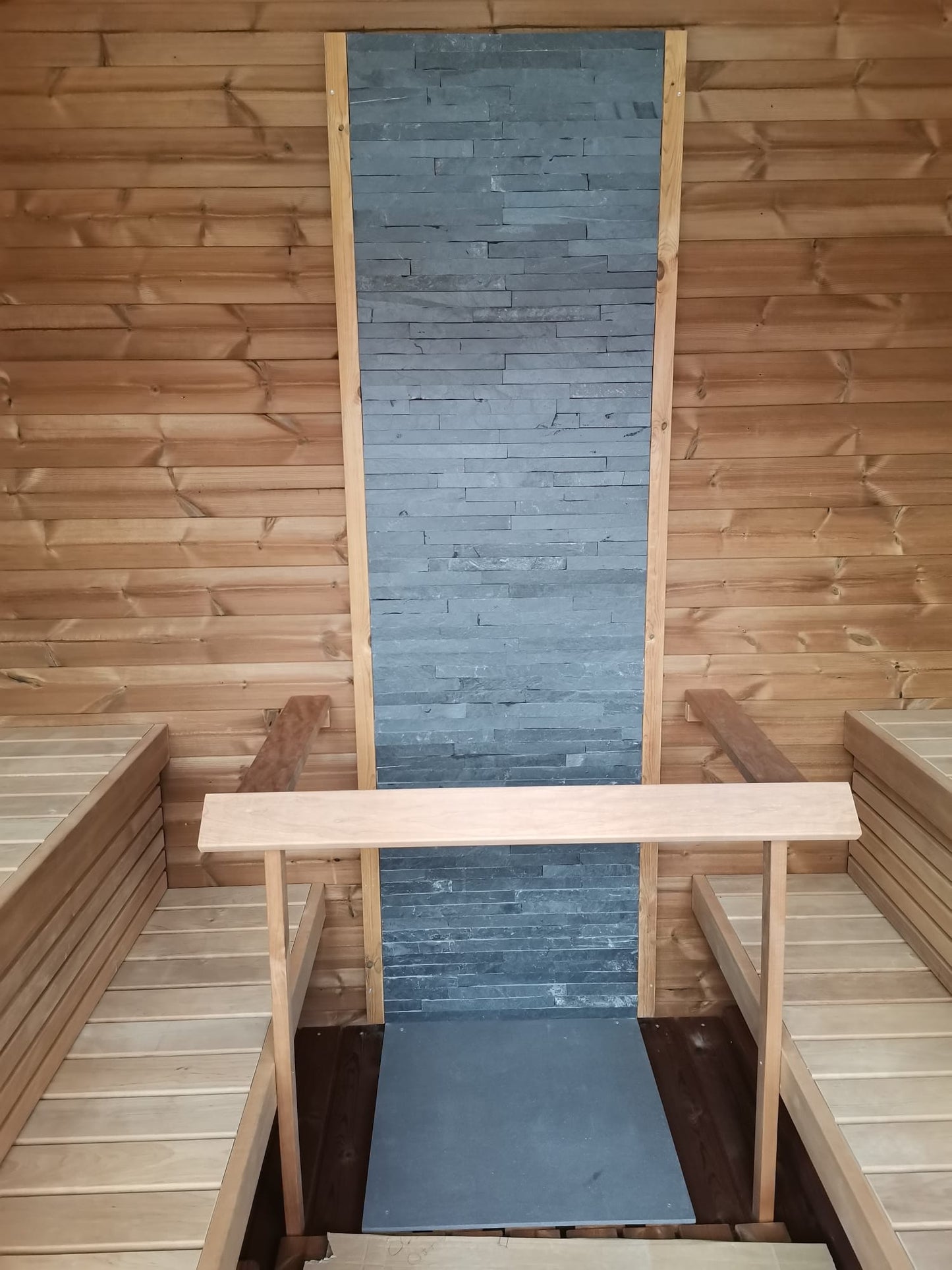 Sauna Saunamo Cubus with stone wall and wooden benches.