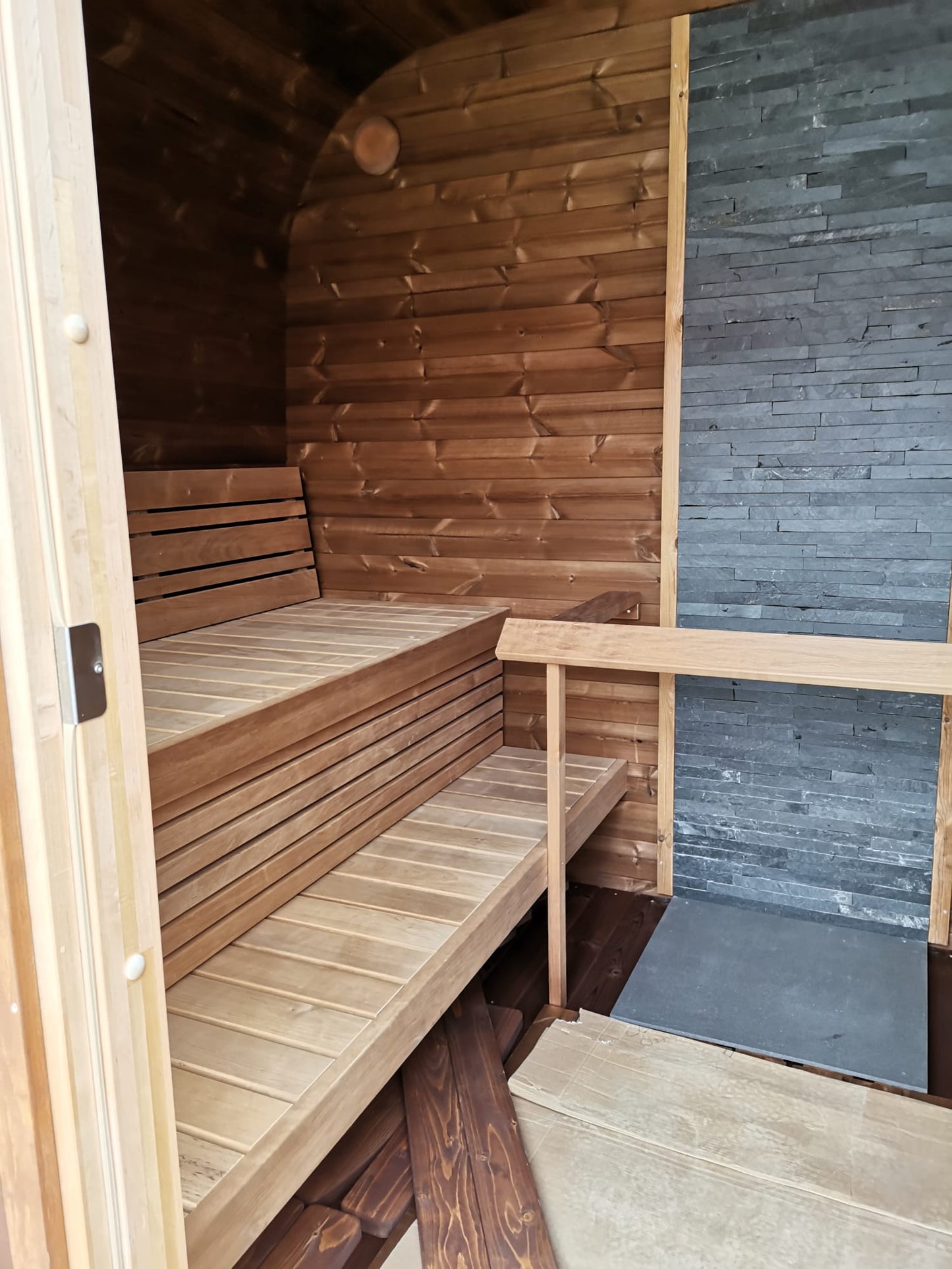 Sauna Saunamo Cubus with partial stone wall.