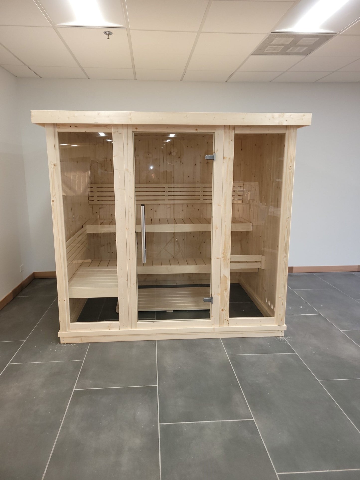 Large wooden indoor sauna with tempered glass doors.