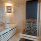 Large indoor sauna with bucket and stones.