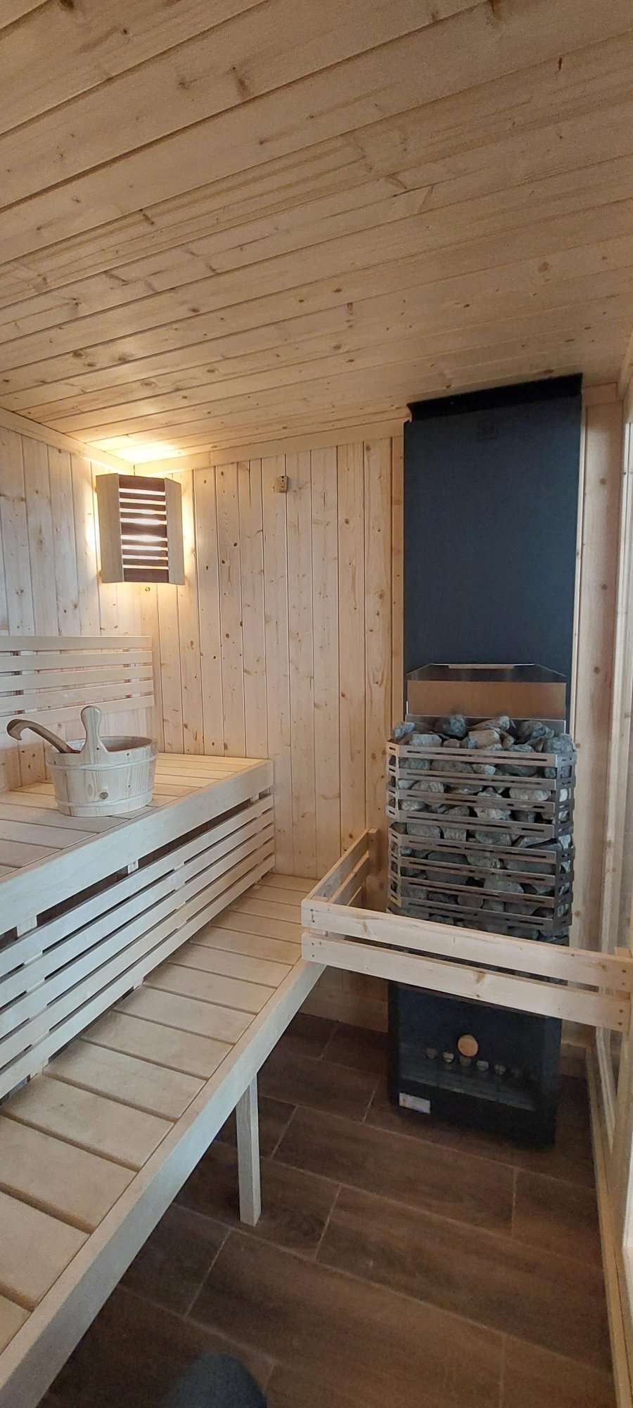 Large indoor sauna with bucket and stones.