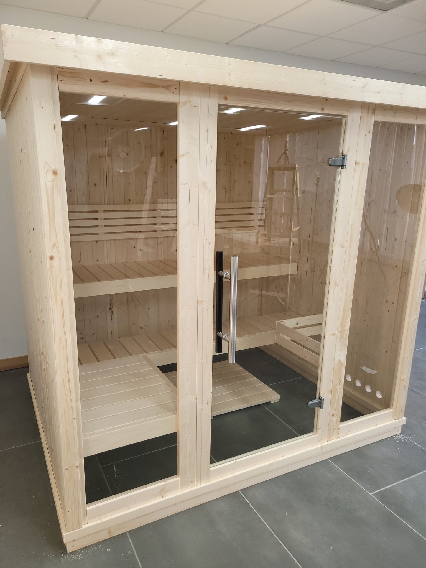 Large wooden indoor sauna with glass doors.