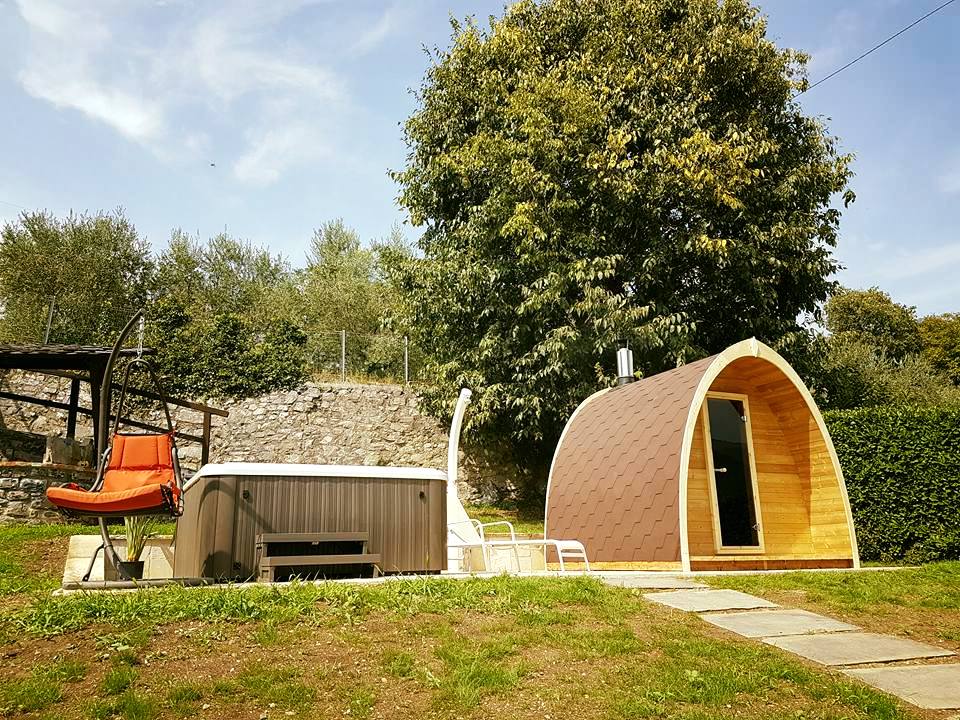 Saunamo Pod next to a wooden hut and garden.